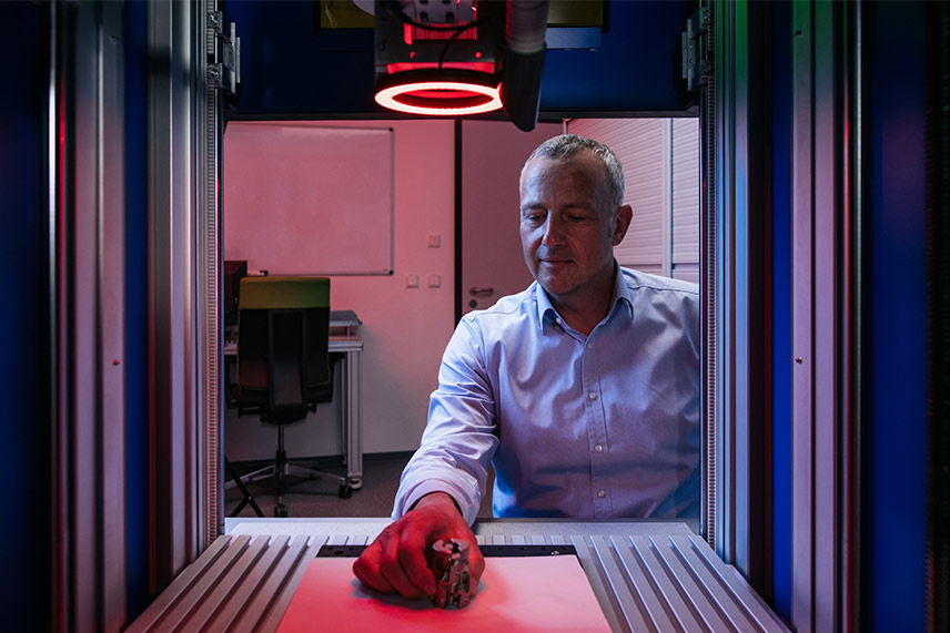 Blick aus Laserstation auf ACI Mitarbeiter, der Bauteil auf T-Nutenplatte platziert