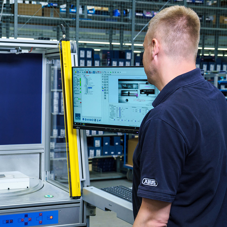 Anlagenbediener schaut auf den PC-Bildschirm einer Laserstation in einer Fertigungshalle