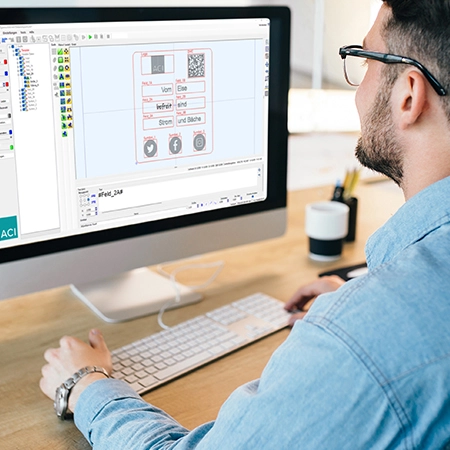 Man at his desk, looking at the user interface of the Magic Mark laser software