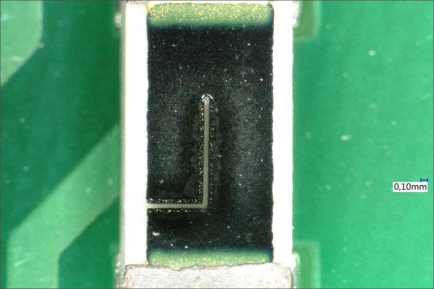 L-cut on an electrical resistor using laser trimming, which sits on a circuit board in the magnification