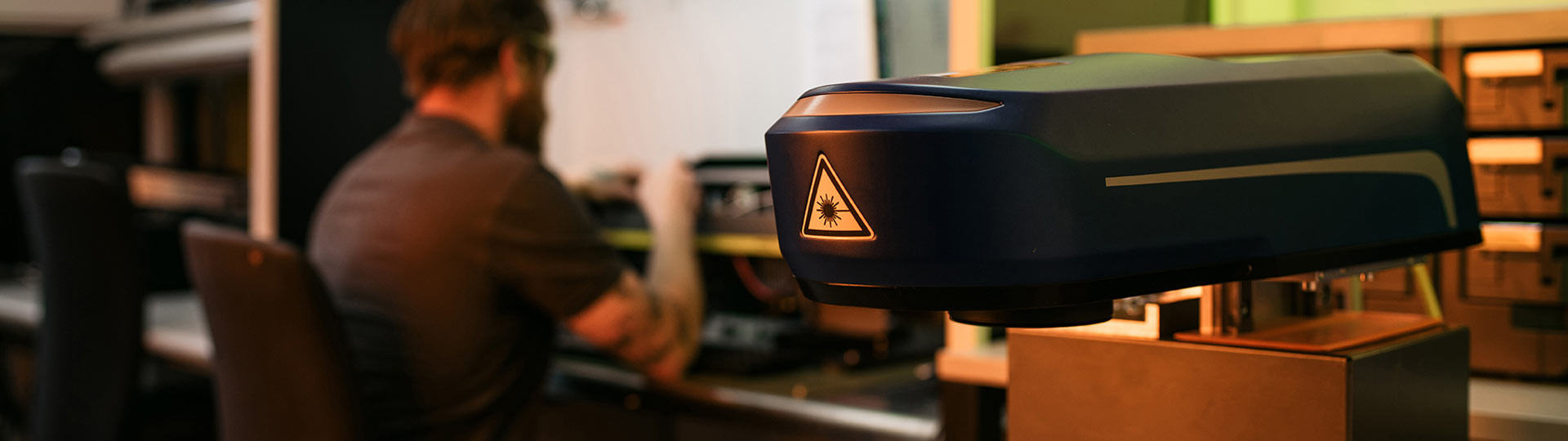 ACI Laser Support-Team im Labor: Mitarbeiter im Hintergrund, Laserkopf im Vordergrund