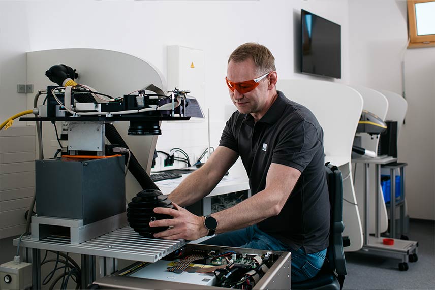 ACI Mitarbeiter mit Laserschutzbrille kalibriert Lasersystem im Labor der optischen Fertigung