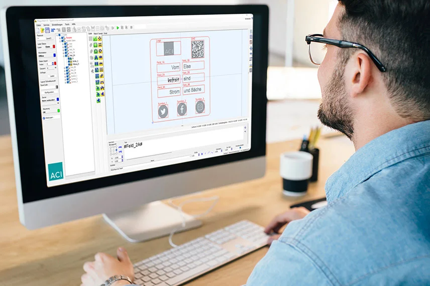 Junger Mann vor PC mit Magic Mark Lasersoftware von ACI auf dem Bildschirm