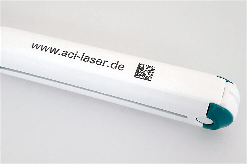 Schwarze Laserbeschriftung mit Text und DMC auf weißem Kunststoff erzeugt mit UV-Laser