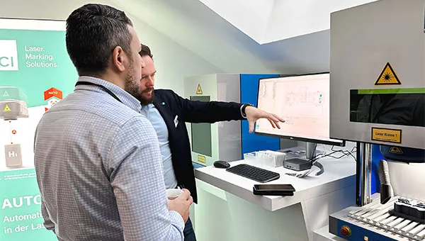 Consultation entre un employé d'ACI et un client devant un système de marquage au laser